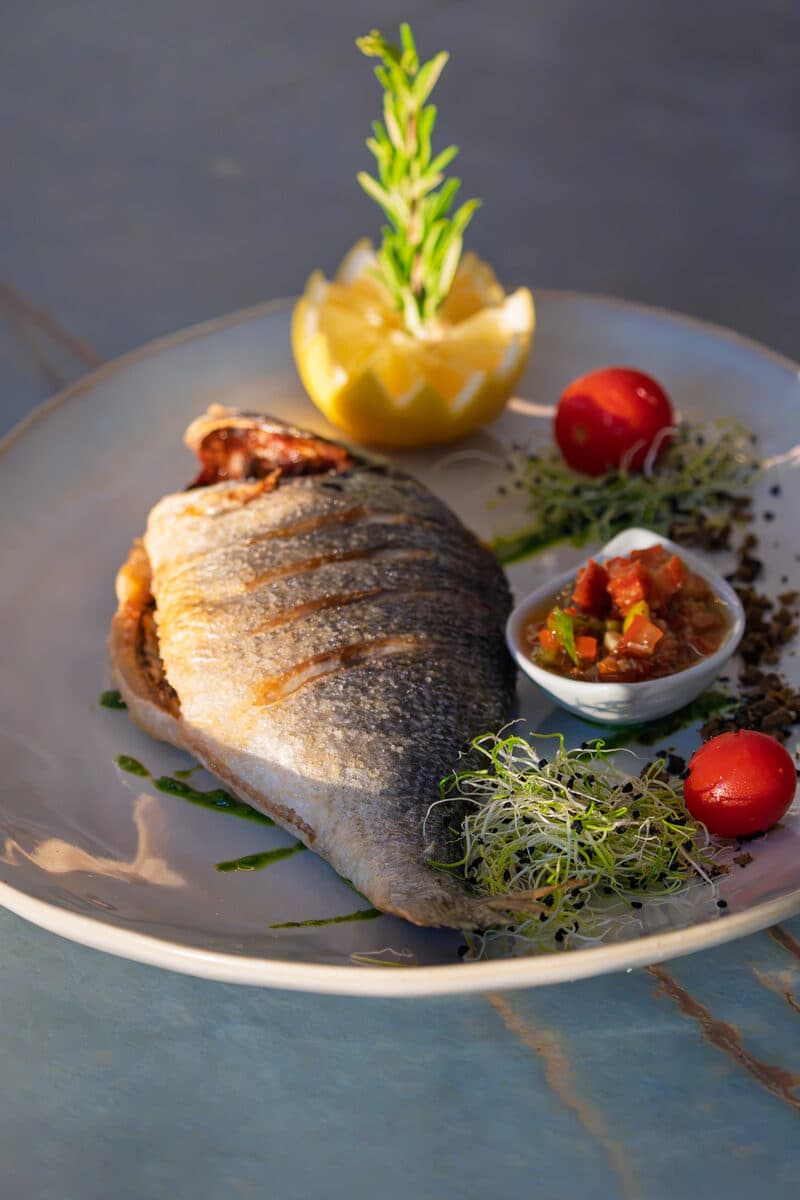 Dorade grillée entière, citron et romarin, sur une table de marbre