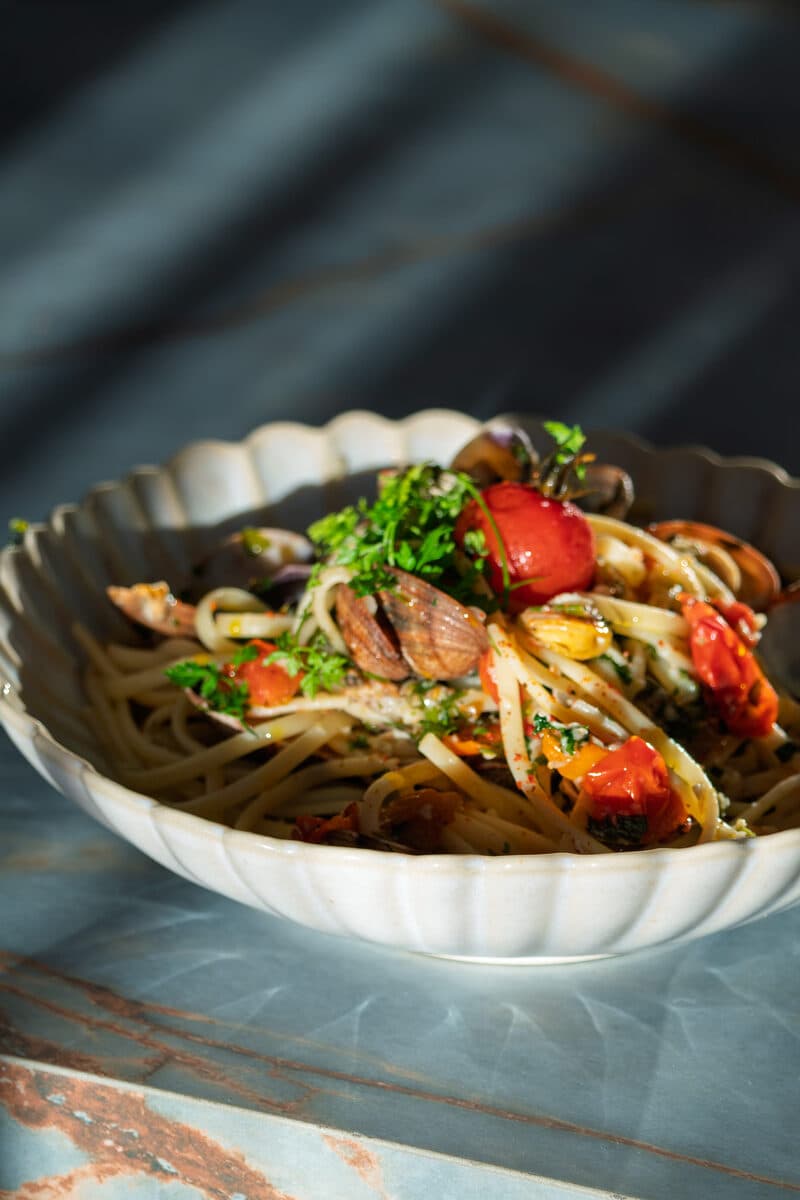 Linguine with clams and candied tomatoes in a ribbed bowl