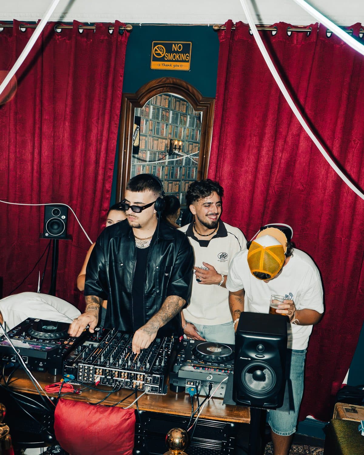 Three people at the decks in front of red curtains